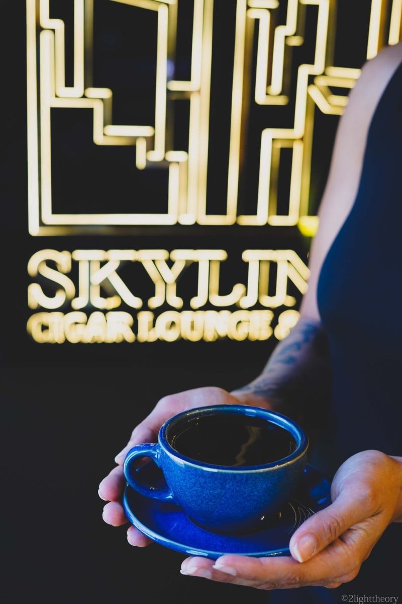 A cup of coffee held under the neon